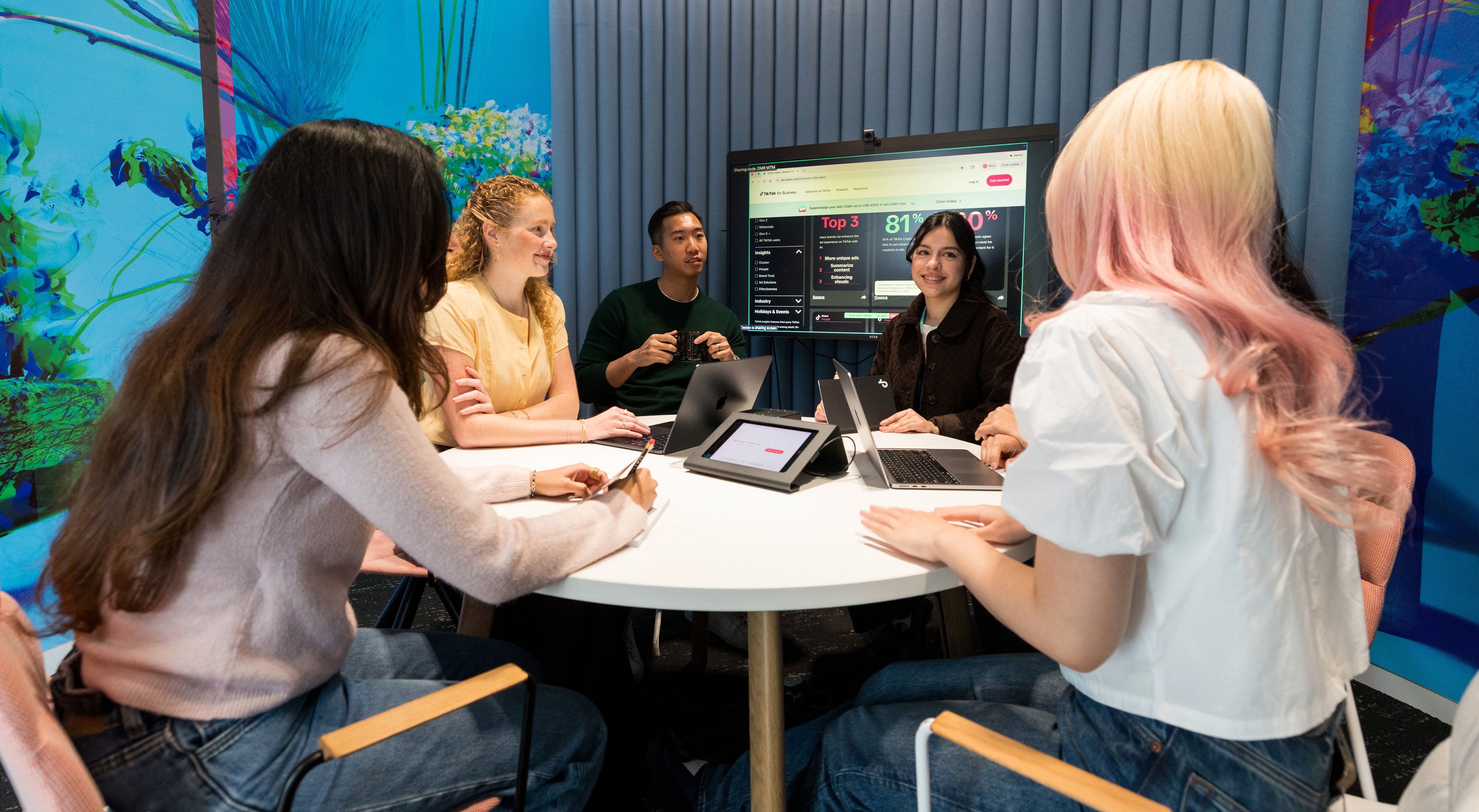 Seven participants in TikTok's Project Intern Program pose together holding boba beverages in an office setting.